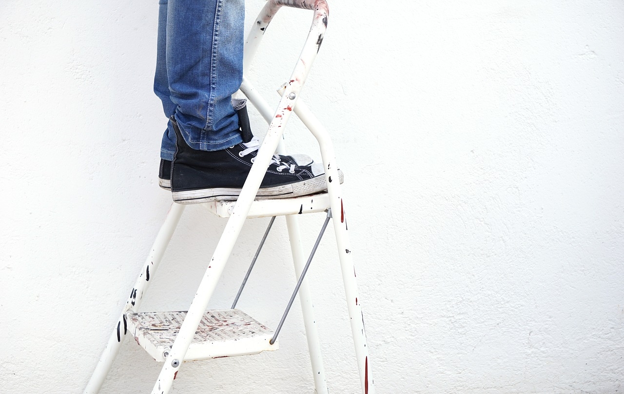 Top step of a ladder, jeans and converse shoes