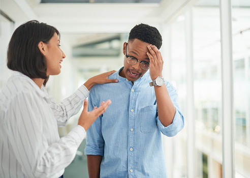 Shot of a young businesswoman comforting her colleague in a modern office