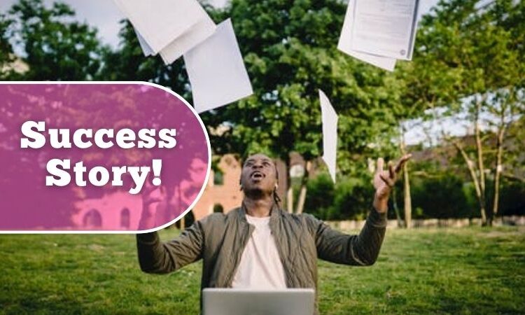 Job success story visual of a man throwing papers in the air sat at a laptop