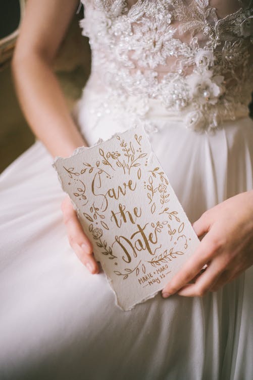 a person in a wedding dress holding a save the date card